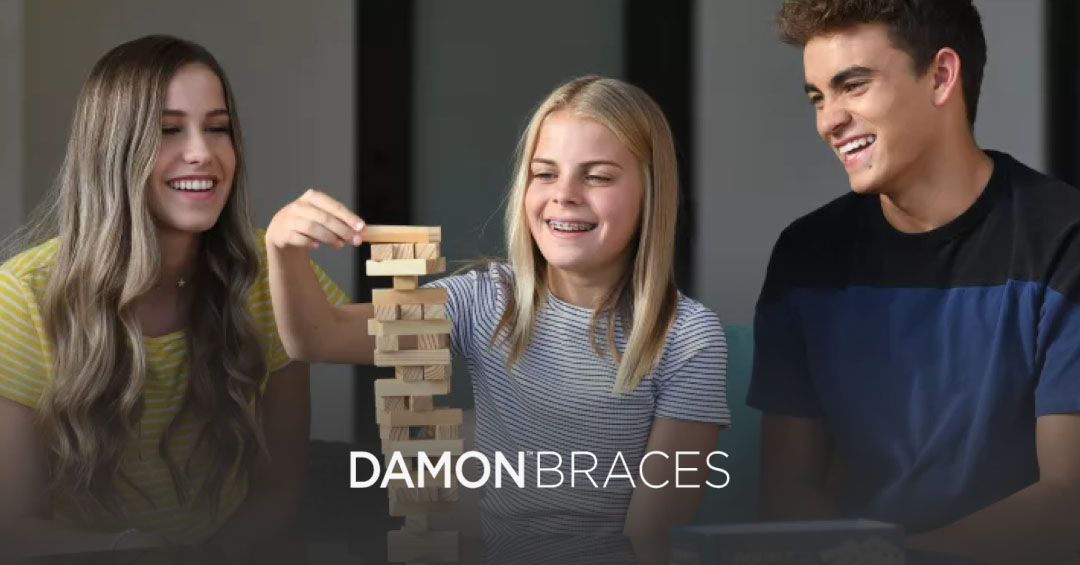 Three people playing Jenga, One person each side watching female person stacking Jenga